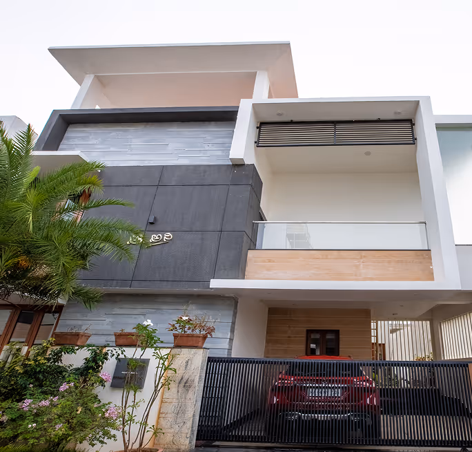 A white villa at Happiness 1, its upper floor cantilevered over a covered car porch.
